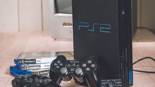 A PS2 games console standing next to some of the best PS2 games and a black controller.